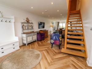 a living room with wooden floors and a staircase at Farne Cottage in Beadnell