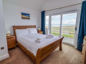 a bedroom with a bed and a large window at Farne Cottage in Beadnell