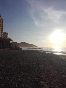 a beach with the sun setting on the ocean at Playa Los Cocos Apat 2 y 3 in Santa Marta