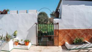 a gate on the side of a building with potted plants at Casa de la Abuela - Encanto rural para grupos in Campofrío