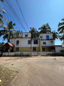 a yellow and white building with palm trees in the background at Comforts Bhairavi INN in Kalyānpur