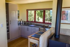 a kitchen with white cabinets and a stove top oven at Sunrise Apartment - Golden Bay in Onekaka