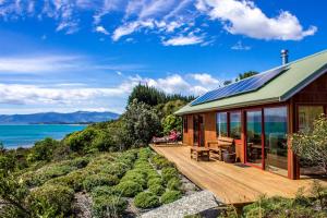 a house with a deck with a view of the ocean at Sunrise Apartment - Golden Bay in Onekaka