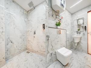 a white bathroom with a shower and a toilet at Olive Aero Suites Plaza Inns Near Delhi International Airport in New Delhi