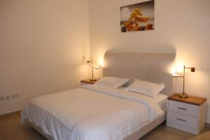 a bedroom with a white bed with two night stands and two lamps at imperial homes 2 in Ajman 
