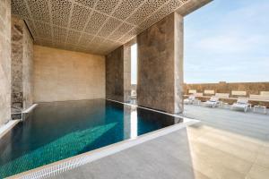 a swimming pool in a large room with chairs and tables at voco Doha West Bay Suites by IHG in Doha +237 photos