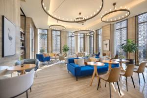 a lobby with a blue couch and tables and chairs at voco Doha West Bay Suites by IHG in Doha