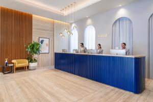 three people working at a desk in a lobby at voco Doha West Bay Suites by IHG in Doha