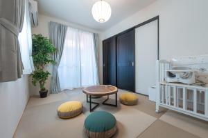 a room with a crib and a table and ottoman at Miyako Island Breeze in Miyako-jima