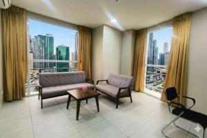 a living room with a couch and a table and windows at LTG Grand Hotel Cebu in Cebu City