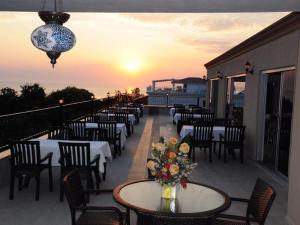 a row of tables and chairs on a balcony with the sunset at Beachway Hotel in Side