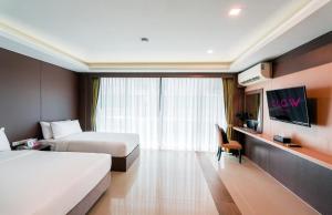 a hotel room with two beds and a flat screen tv at GLOW Pattaya in Pattaya South