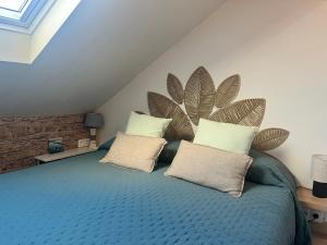 a bedroom with a blue bed with two pillows at Sur les Toits de Honfleur in Honfleur