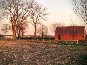 a red barn in the middle of a field at Vakantiewoning Vaib in Kortemark