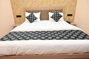 a bedroom with a white bed with black and white pillows at Hotel Pinaka in Pratāpgarh