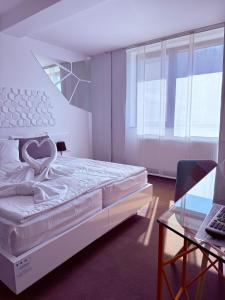 a white bedroom with a bed and a glass table at Niro Residence in Gura Humorului