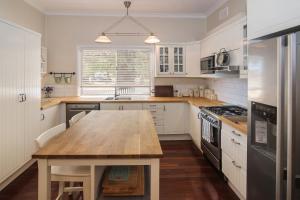 a kitchen with white cabinets and a wooden table at Sea La Vie in Busselton