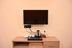 a tv on a wall with a coffee maker on a table at Hotel Pinaka in Pratāpgarh