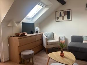 a living room with a tv and a couch and a table at Sur les Toits de Honfleur in Honfleur