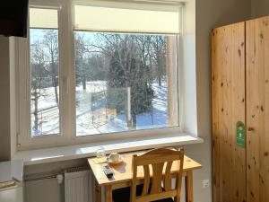 a wooden table and chair in front of a window at Kuremaa Külalistemaja in Kuremaa