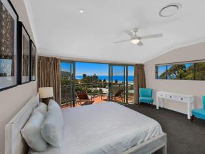 a white bed sitting in a bedroom next to a window at Avoca Palms Resort in Avoca Beach