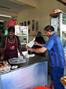 two men standing in a kitchen preparing food at Betel Box Backpackers Hostel in Singapore