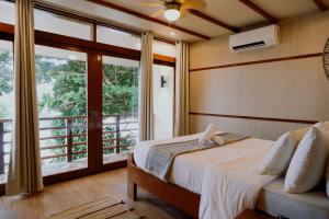 a bedroom with a bed and a large window at Katig Beachfront Boutique Hotel in General Luna