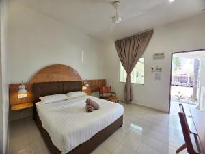 a bedroom with a bed with a teddy bear on it at Casa Yusika in Pantai Cenang