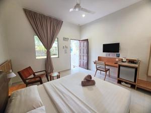 a room with a bed and a desk and a television at Casa Yusika in Pantai Cenang