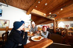 un grupo de personas sentadas en una mesa comiendo pizza en Abom Hotel, en Mount Buller