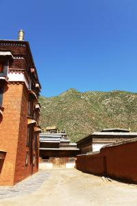 a group of buildings with a mountain in the background at Overseas Tibetan Hotel in Xiahe