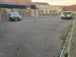 two cars parked in a parking lot next to a fence at Prestige Loft-Cinéma Privé-King Size-Parking Gratuit-5 min Aéroport Beauvais in Beauvais