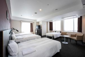 a hotel room with three beds and a table at Smile Hotel Kyoto Shijo in Kyoto +52 photos