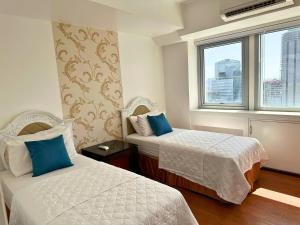 a hotel room with two beds and a window at Grand Cenia Residences in Cebu City