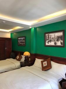 two beds in a room with green walls at Khách Sạn Nguyễn Hùng in Sapa