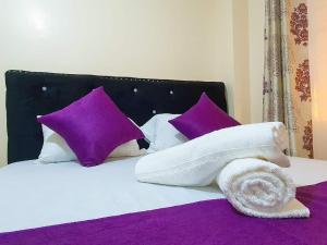 a bed with purple pillows and a towel on it at Blissful one bedroom in Ruiru in Ruiru
