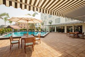 a patio with tables and chairs and an umbrella at ARISTA BY AMBITION in Guwahati
