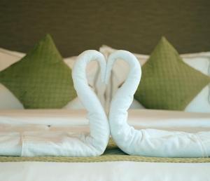 two white swans sitting on a bed with pillows at Lazo EcoSpot Vythiri , Wayanad in Vythiri