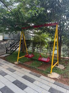 a playground with two red swings in a park at Lazo EcoSpot Vythiri , Wayanad in Vythiri