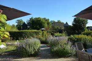 a garden with purple flowers and bushes and an umbrella at Bienvenu dans le Java chez Pommes & Chevaux in Favières