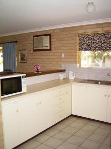 a kitchen with white cabinets and a microwave at Kalbarri Riverfront Unit in Kalbarri