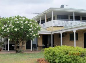 a house with a flowering tree in front of it at Kalbarri Riverfront Unit in Kalbarri