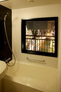 a bathroom with a bath tub and a window at Hotel Trusty Osaka Abeno in Osaka