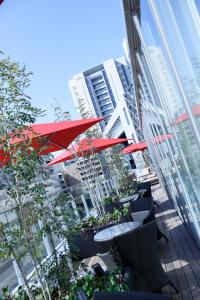 a patio with tables and red umbrellas in front of a building at Hotel Trusty Osaka Abeno in Osaka