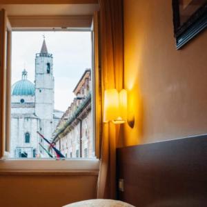 a bedroom with a window with a view of a church at Residenza dei Capitani - Piazza del Popolo in Ascoli Piceno
