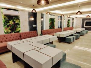 a restaurant with tables and benches and plants on the walls at HOTEL JVS PALACE in Gorakhpur