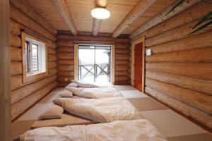 a row of beds in a room with wooden walls at ヴィラ湖西 最大11名 琵琶湖ビュー165平米の一棟貸切ログハウス BBQハウス完備 広々3LDK ロフト Wi-Fi in Takashima