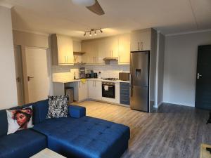 a living room with a blue couch and a kitchen at Manchester Heights in Cape Town