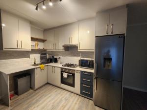 a kitchen with white cabinets and a stainless steel refrigerator at Manchester Heights in Cape Town