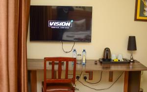 Ein Fernseher an der Wand über einem Schreibtisch mit einem Stuhl in der Unterkunft Cicada Hotel in Eldoret